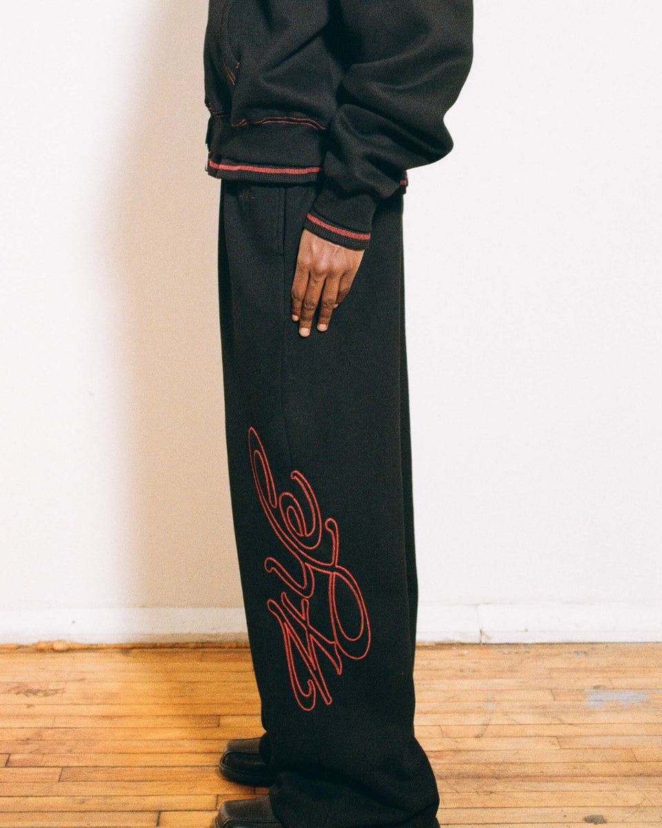 Model wearing Signature Wide Pant - Black/Red on a wooden floor.