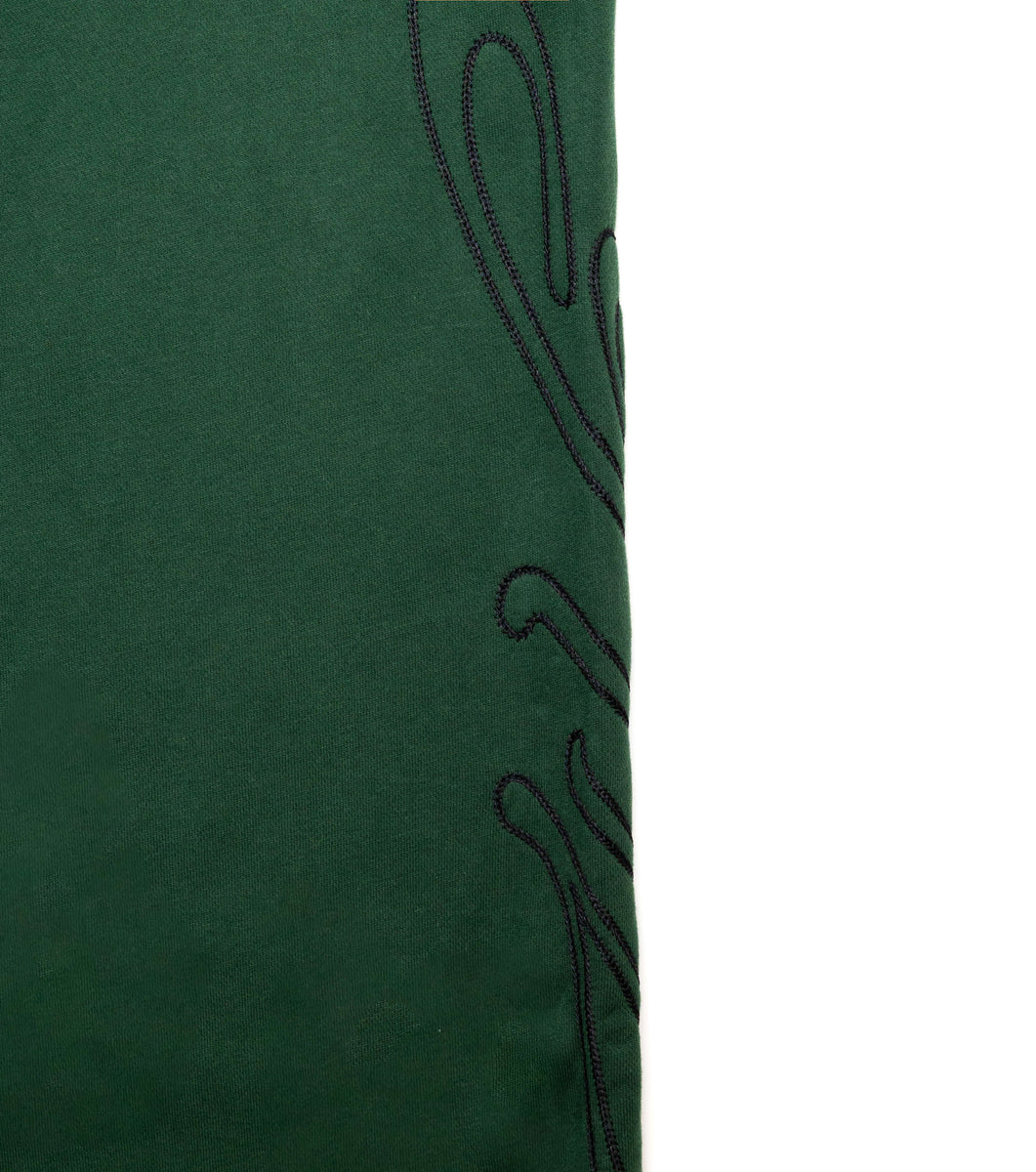 Close up of black signature logo on dark green pants