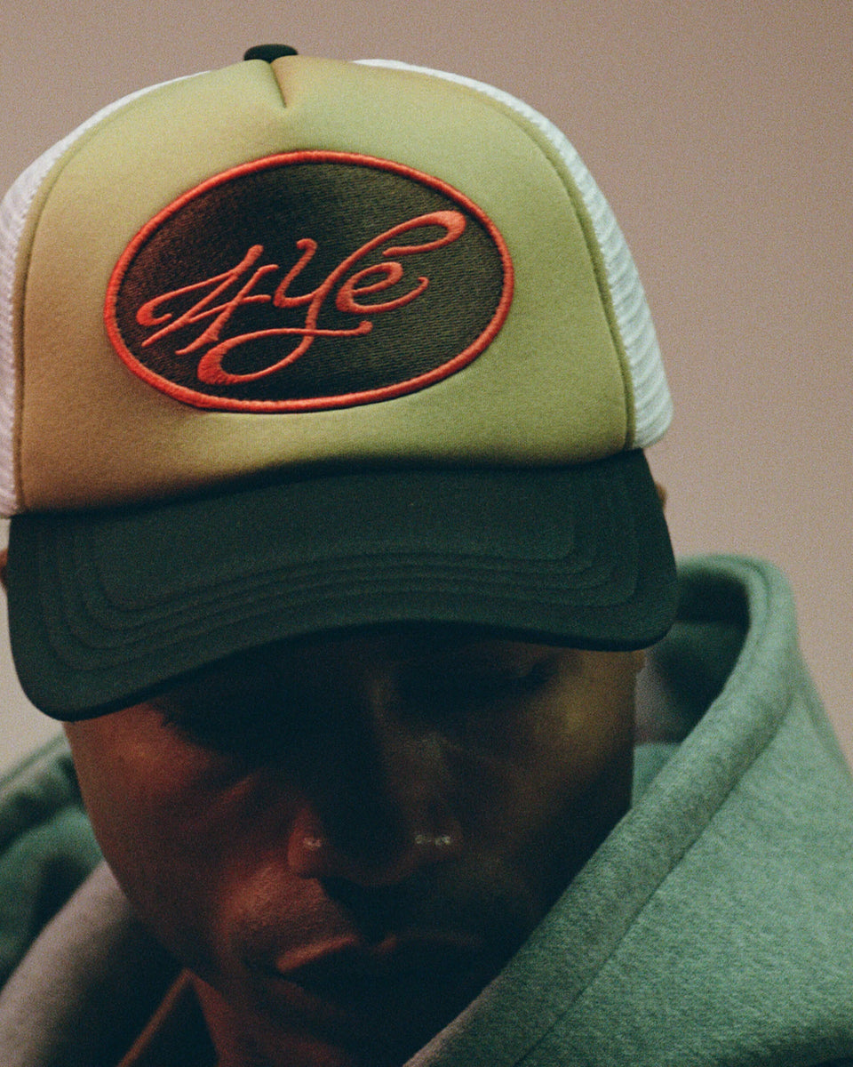 model wearing a black and beige cap with a logo on a neutral background