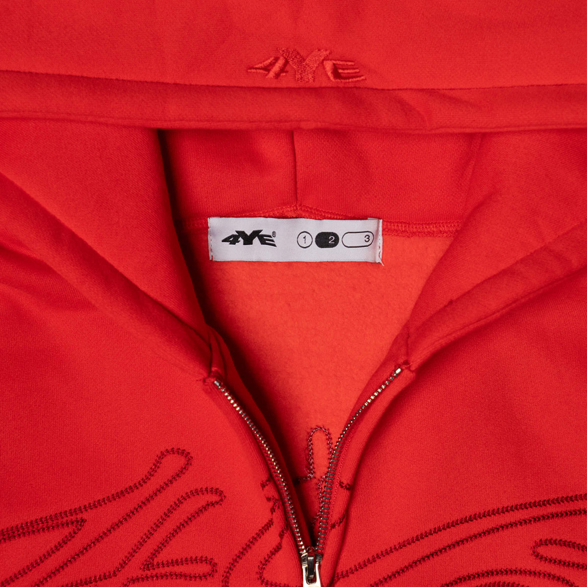 Close-up view of the 4YE Signature Logo Zip Hoodie in Red. The hoodie features 325 GSM brushed medium weight fleece offering ultimate comfort and warmth, including high-quality chain stitch embroidery and a 2-way YKK zipper, showcasing a trendy cropped and boxy fit.