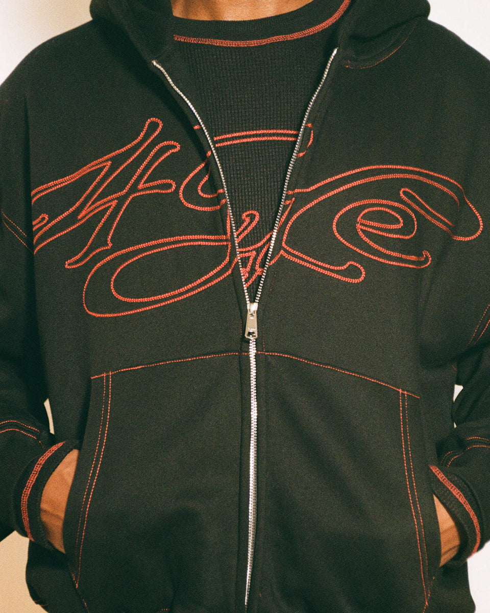 Black signature zip up with red stitching neutral background