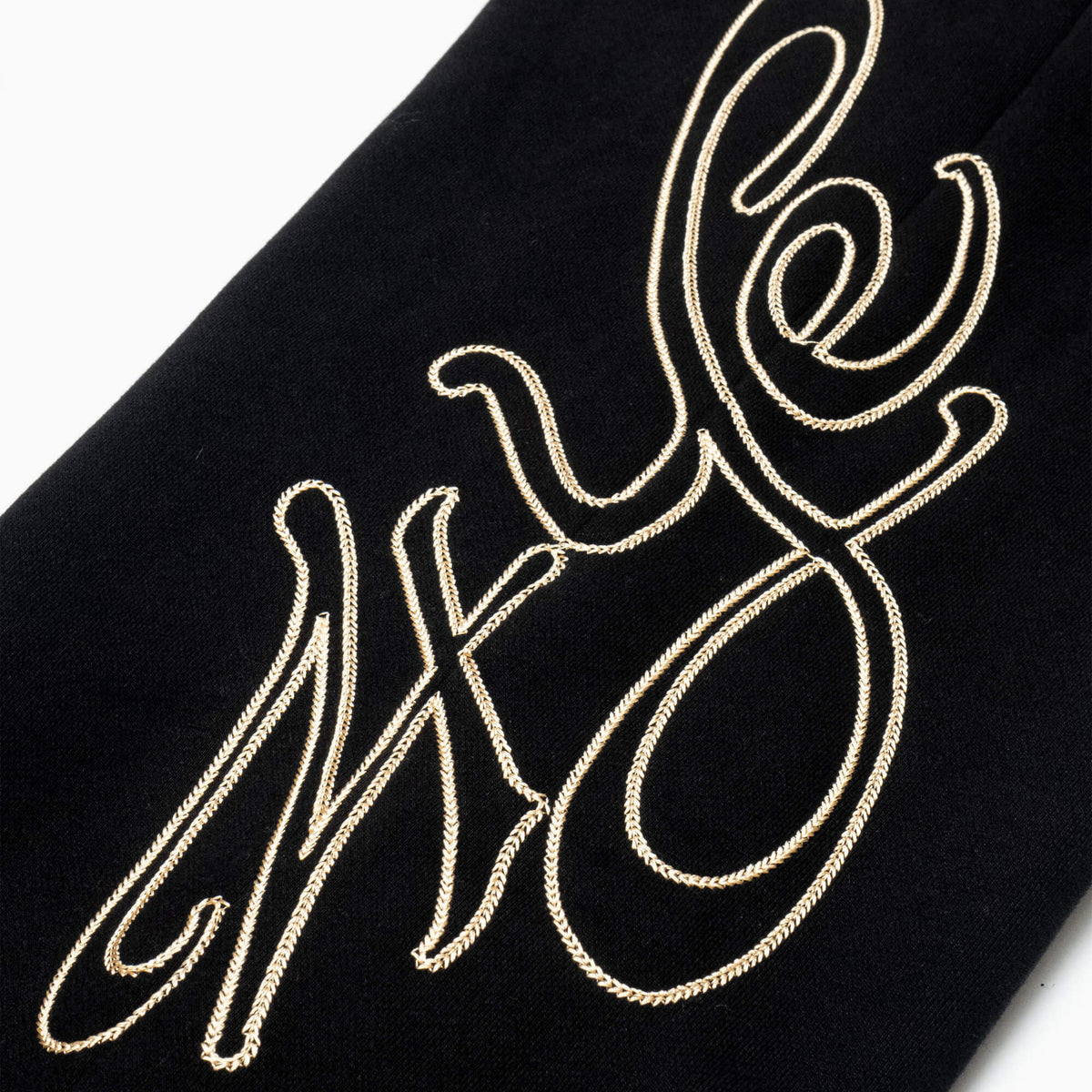 Close up of 4YE chain stitched logo detail in gold contrast stitching.