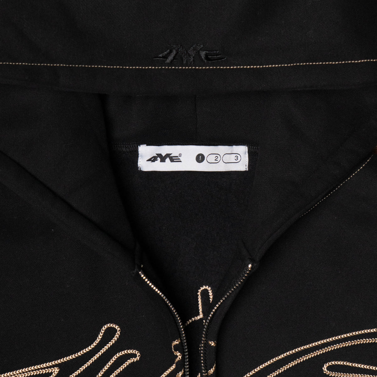 Close-up view of the 4YE Signature Logo Zip Hoodie in Black. The hoodie features 325 GSM brushed medium weight fleece offering ultimate comfort and warmth, including high-quality chain stitch embroidery and a 2-way YKK zipper, showcasing a trendy cropped and boxy fit.